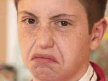 a young boy with freckles is making a funny face with his mouth open .