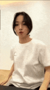 a woman wearing a white t-shirt with a square on the left side