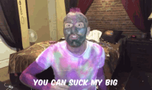 a man with a purple shirt and a black face mask says you can suck my big