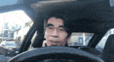 a man wearing glasses is driving a car with a sticker on the windshield that says mcdonald 's