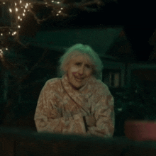 an elderly woman with a bandage on her face looks out a window