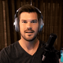 a man wearing headphones and a black shirt is standing in front of a microphone