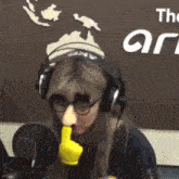 a woman wearing headphones is standing in front of a microphone holding a stuffed orange .