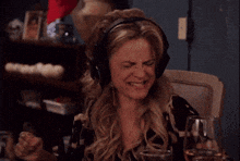 a woman wearing headphones is laughing with a glass of wine in front of her