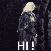 a black and white photo of a woman standing next to a brick wall with the words hi written in white