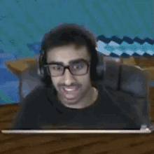 a man wearing glasses and headphones is sitting in front of a computer screen .