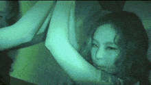 a girl 's face is visible in a blurry photo with a green background