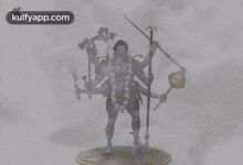 a statue of a man with many hands holding a sword and a spear .