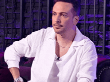 a man in a white shirt is sitting on a purple chair