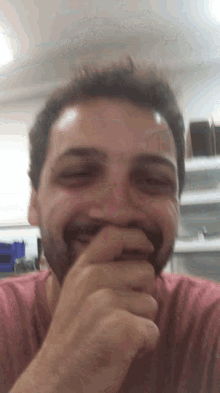 a man with a beard is smiling and covering his mouth with his hand