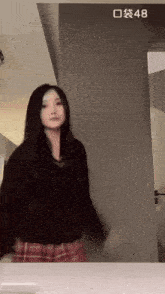 a woman is dancing in front of a wall with the number 48 written on it