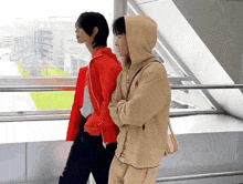 two men standing next to each other one wearing a hoodie