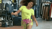 a woman in a neon yellow shirt is dancing in a clothing store .