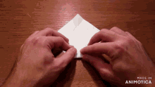 a person folding a piece of paper with the words made in animotica below