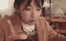 a woman is sitting at a table drinking a glass of soda .