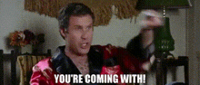 a man in a robe is saying `` you 're coming with '' while holding a microphone .