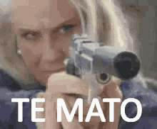 a woman is pointing a gun at the camera with the words te mato written on the bottom .