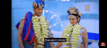 a man and a woman are standing next to each other wearing garlands of bananas and flowers .