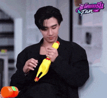 a man in a black jacket is holding a toy chicken in front of a fan live sign