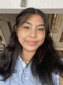 a woman wearing a blue and white striped shirt is smiling for the camera