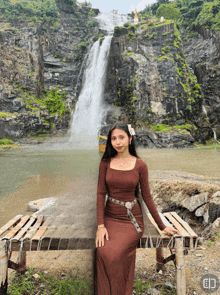 a woman sitting on a bench in front of a waterfall
