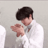a man in a white shirt is holding his hands together .