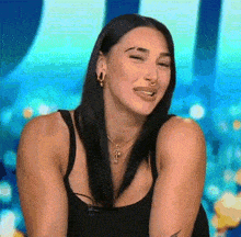 a woman wearing a black tank top and a nose ring is smiling .