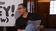 a man is sitting in front of a sign that says ey
