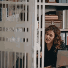 a woman is sitting at a desk in front of a laptop computer in an office .