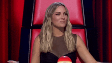 a woman in a black dress is sitting in a red chair with a red ball in front of her .