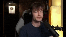 a young man wearing headphones is sitting in front of a microphone .