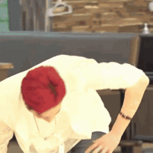 a man with red hair is wearing a white shirt and a watch while bending over .