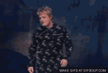 a man in a black shirt is dancing with his arms outstretched .