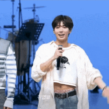 a man in a crop top is holding a microphone