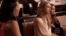 a group of women are sitting on a couch talking to each other in a room .
