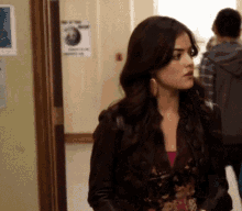 a woman in a leather jacket is standing in a hallway with a sign on the wall that says ' no smoking '