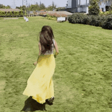 a woman in a long yellow skirt is running in a grassy field