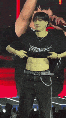 a man is standing on a stage taking off his shirt .