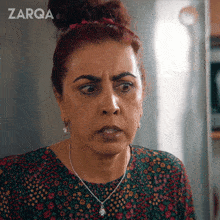 a woman with a bun and a necklace with the word zarqa on the bottom right