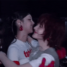 two women are hugging each other in a dark room and kissing each other .