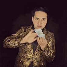a man in a gold jacket is holding a bunch of money in his hands