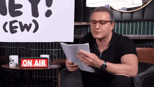 a man reading a script in front of a sign that says on air