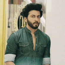 a man with a beard and a green shirt is standing in front of a mirror