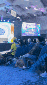 a group of people sitting in chairs in front of a large screen that says ' e-sports ' on it