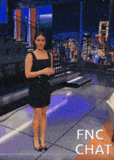 a woman in a black dress is standing on a stage with the words fnc chat behind her