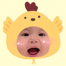 a baby wearing a yellow chicken hat with a heart on its head