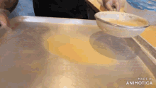 a person is pouring something into a bowl with the words made in animotica visible