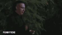 a man with a mohawk is standing in front of a tree in the dark .
