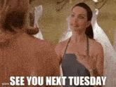 a woman in an apron is talking to another woman in a bridal store .