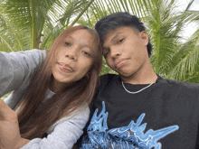 a boy and a girl are posing for a picture and the boy is wearing a black shirt with a blue design on it